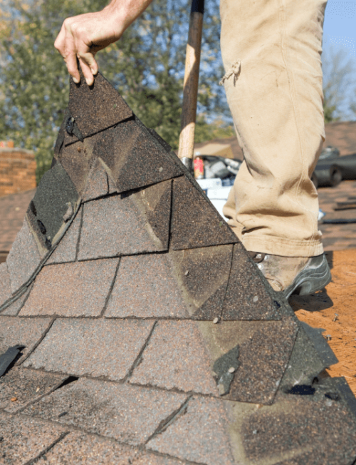 worker removing the roofing tiles of a roof of a house